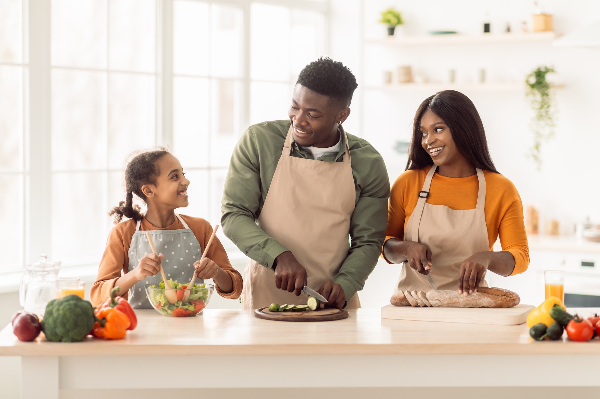 Black Family Cooking Together Making Salad Standing In Modern Kitchen